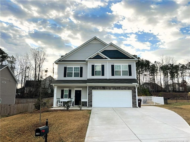 view of front of house with an attached garage, covered porch, driveway, and fence