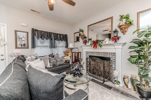 living area with a fireplace, wood finished floors, visible vents, and ceiling fan