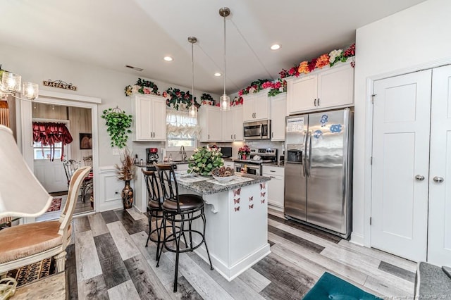 kitchen with visible vents, a breakfast bar, a sink, appliances with stainless steel finishes, and white cabinetry