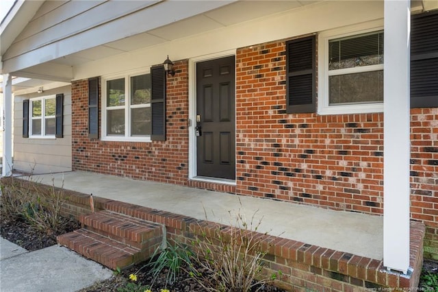 doorway to property with brick siding and a porch