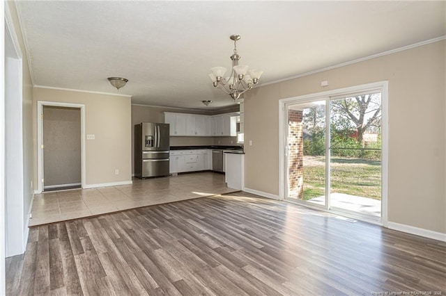 unfurnished living room featuring a notable chandelier, wood finished floors, and ornamental molding