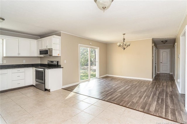 kitchen with dark countertops, ornamental molding, light wood-style flooring, stainless steel appliances, and white cabinetry