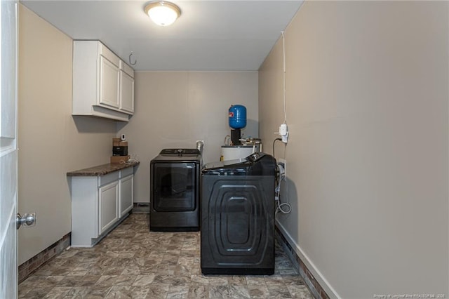 laundry area with stone finish floor, cabinet space, baseboards, and washing machine and clothes dryer