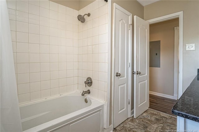 full bathroom featuring electric panel, shower / bath combo with shower curtain, and baseboards