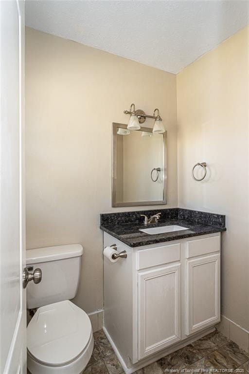 bathroom featuring toilet, vanity, and baseboards