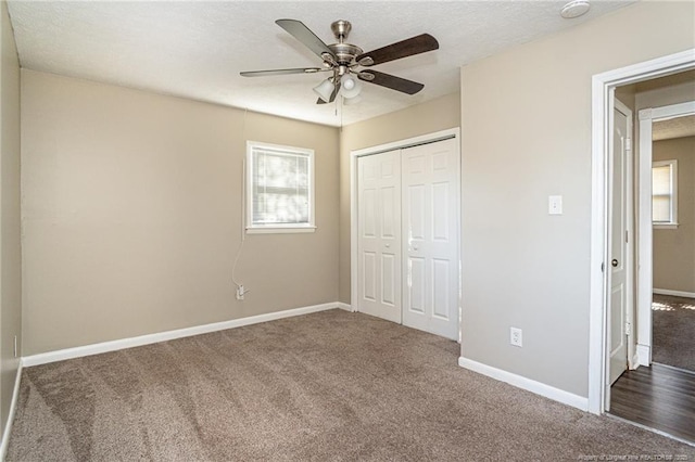 unfurnished bedroom featuring baseboards, carpet floors, ceiling fan, a closet, and a textured ceiling