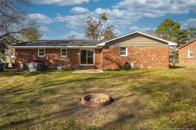 back of house with entry steps, a yard, and brick siding