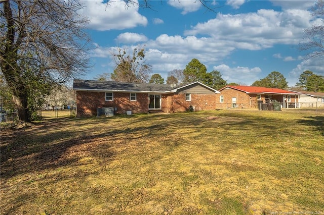 rear view of house featuring a lawn, central AC, brick siding, and fence