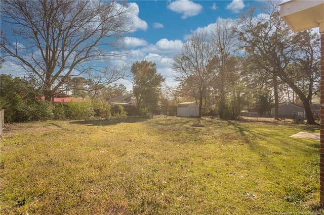 view of yard featuring an outdoor structure, fence, and a shed