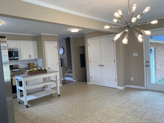 kitchen featuring white cabinetry, appliances with stainless steel finishes, crown molding, decorative backsplash, and a chandelier