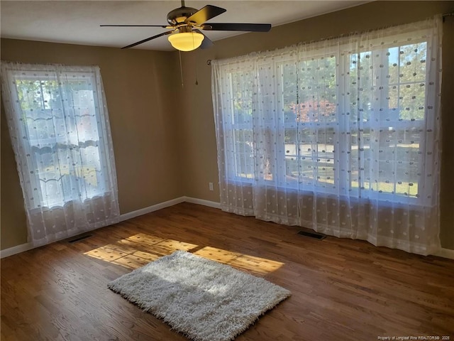 empty room with visible vents, a healthy amount of sunlight, and wood finished floors