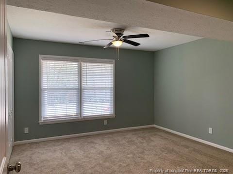 carpeted empty room featuring a ceiling fan and baseboards