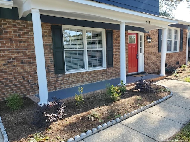 view of exterior entry featuring crawl space and brick siding