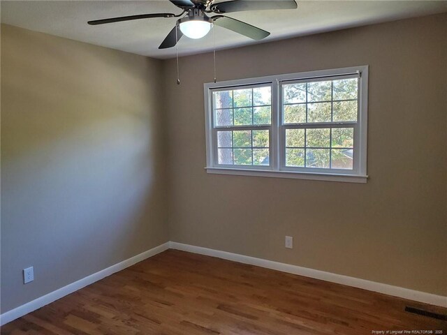 empty room featuring visible vents, wood finished floors, and baseboards