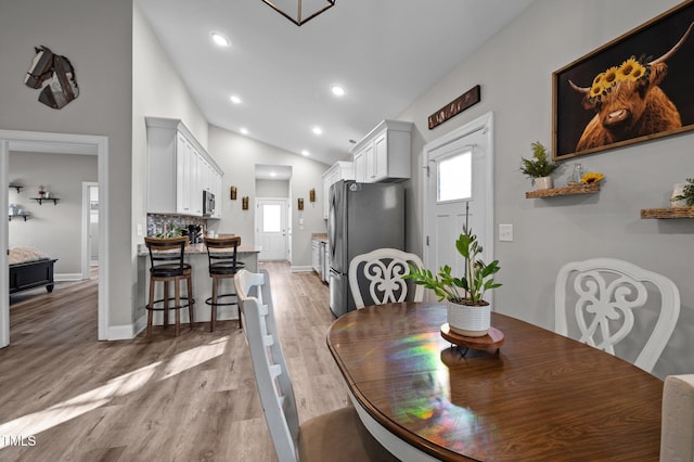 dining area featuring recessed lighting, light wood-style flooring, baseboards, and vaulted ceiling