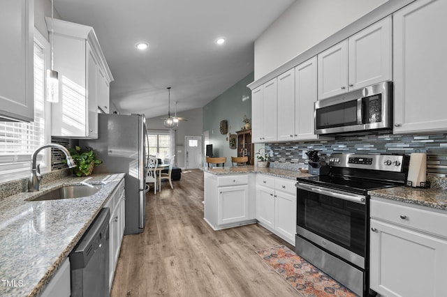 kitchen featuring light wood finished floors, ceiling fan, a sink, appliances with stainless steel finishes, and tasteful backsplash