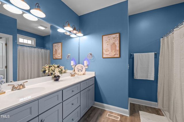 bathroom with baseboards, wood finished floors, visible vents, and a sink