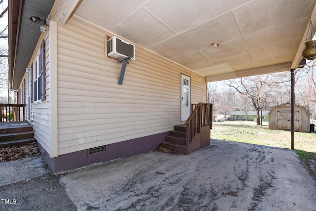 view of patio / terrace with an outdoor structure, a wall unit AC, and a shed