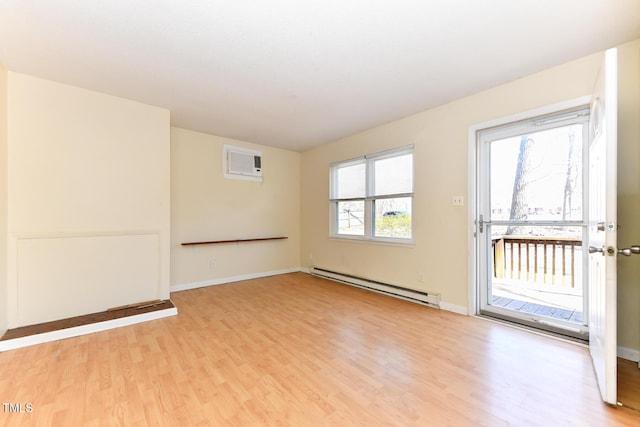 spare room with a wall mounted air conditioner, light wood-type flooring, baseboards, and a baseboard radiator