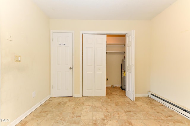 unfurnished bedroom featuring a baseboard radiator, baseboards, electric water heater, and a closet