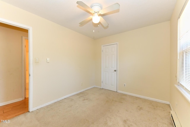 empty room with light carpet, a ceiling fan, baseboards, and a baseboard radiator