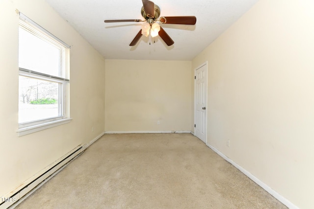 empty room featuring light carpet, baseboard heating, a ceiling fan, and baseboards