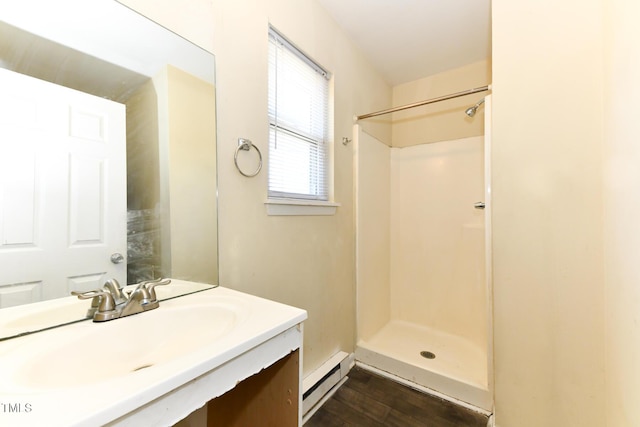 bathroom with wood finished floors, vanity, a shower, and a baseboard radiator