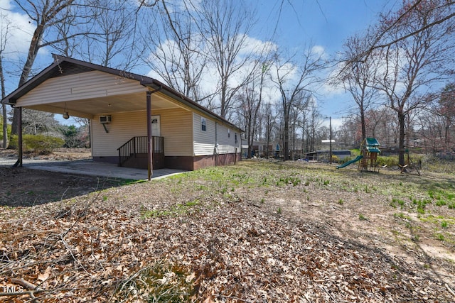 view of yard with an attached carport, an AC wall unit, and a playground