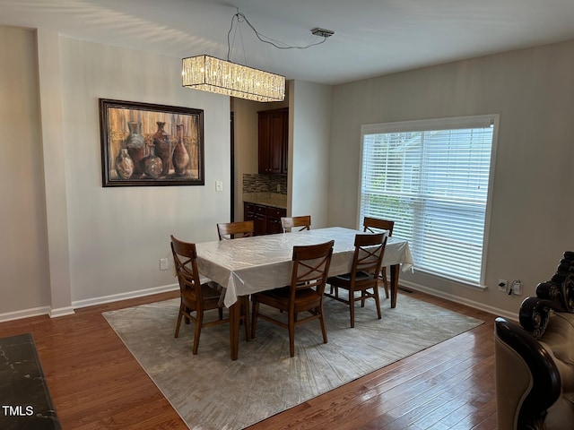 dining space featuring an inviting chandelier, baseboards, and dark wood-type flooring