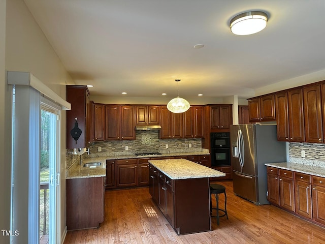 kitchen featuring a kitchen island, stainless steel fridge with ice dispenser, wood finished floors, gas stovetop, and a sink