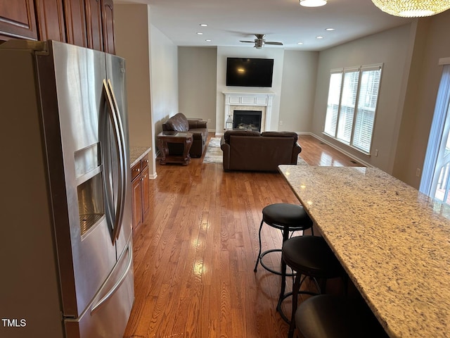 kitchen featuring light wood-style flooring, a breakfast bar area, stainless steel refrigerator with ice dispenser, and ceiling fan