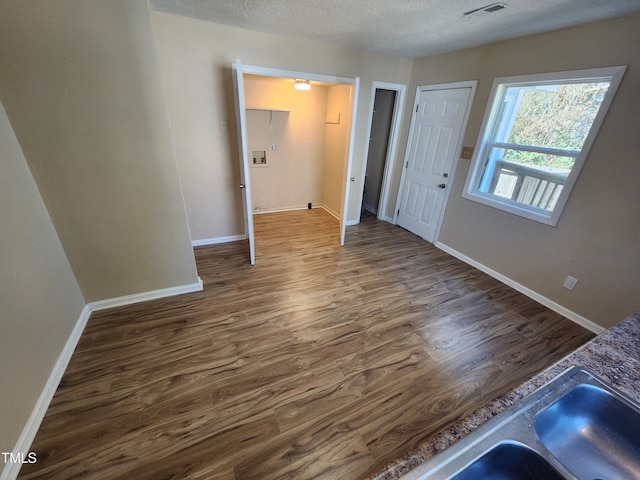 interior space featuring visible vents, a textured ceiling, baseboards, and wood finished floors