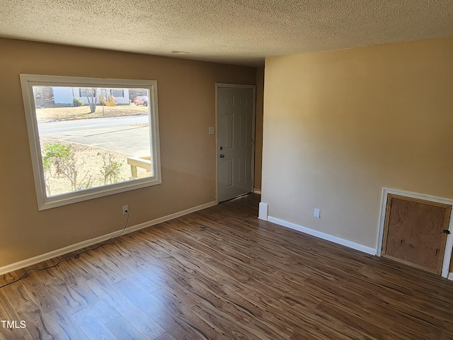 spare room with dark wood finished floors, a textured ceiling, and baseboards