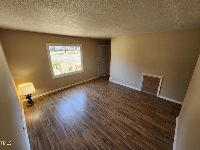 unfurnished room with baseboards, dark wood-type flooring, and a textured ceiling