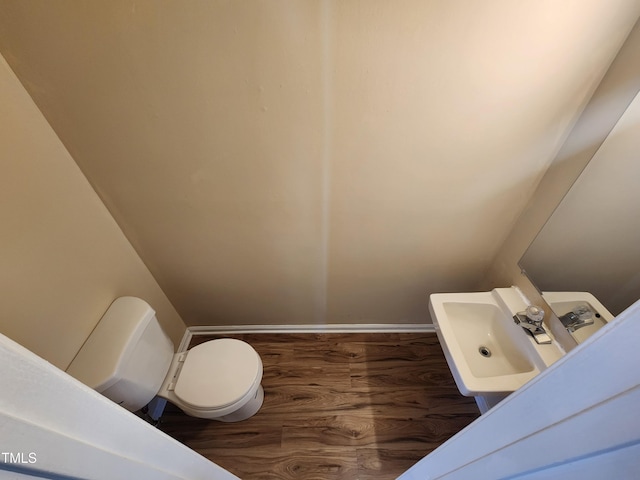 bathroom with a sink, baseboards, toilet, and wood finished floors