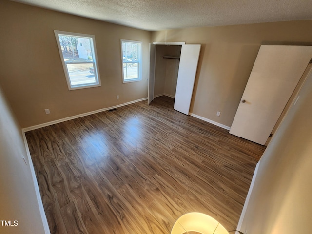 unfurnished bedroom with visible vents, baseboards, a textured ceiling, and wood finished floors