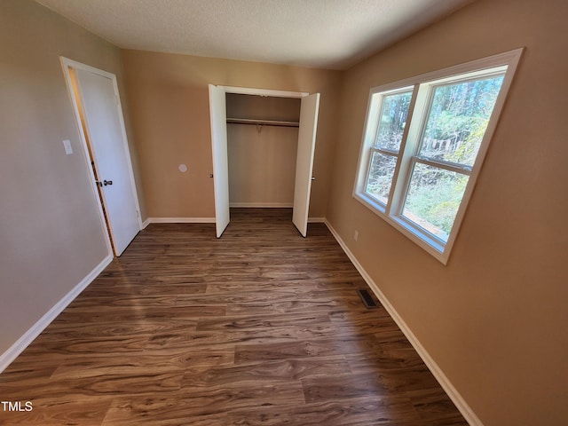 unfurnished bedroom with visible vents, baseboards, dark wood finished floors, a closet, and a textured ceiling