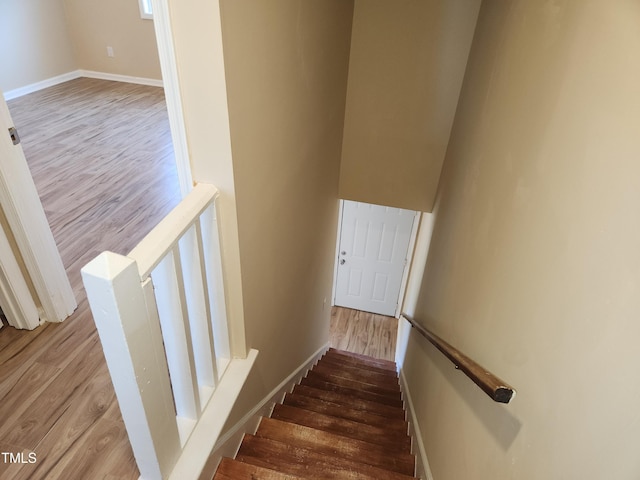 stairway with wood finished floors and baseboards