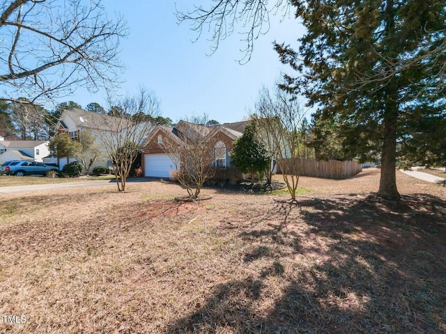 view of yard featuring an attached garage, driveway, and fence