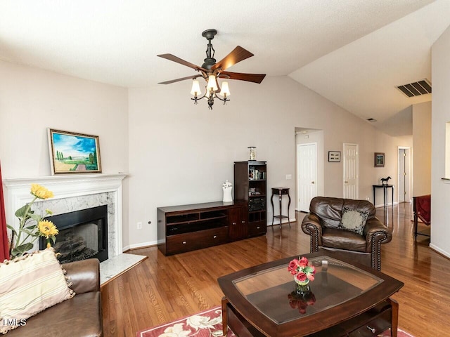 living room featuring wood finished floors, visible vents, a premium fireplace, ceiling fan, and vaulted ceiling