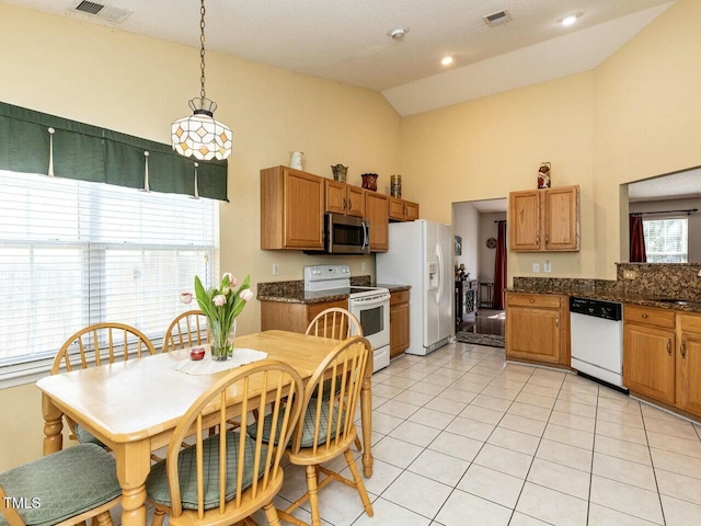 kitchen with visible vents, high vaulted ceiling, dark countertops, white appliances, and light tile patterned floors