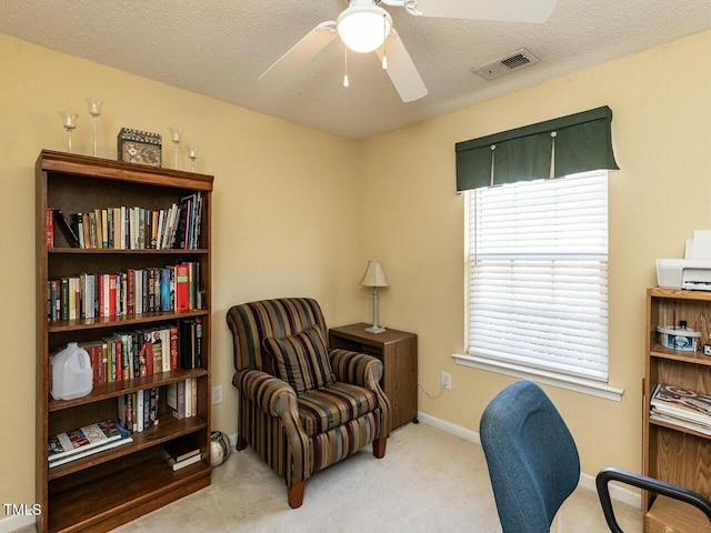 carpeted office space with baseboards, visible vents, a textured ceiling, and a ceiling fan