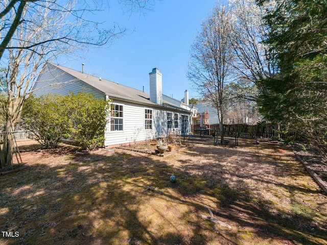 back of house with a chimney and fence