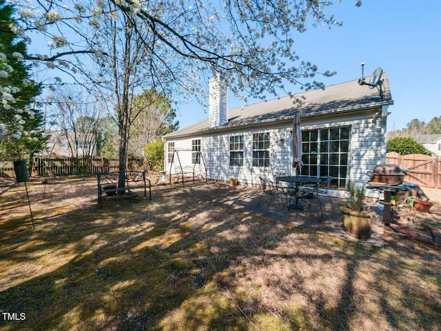 back of property with a gate, fence, a yard, a chimney, and a patio area