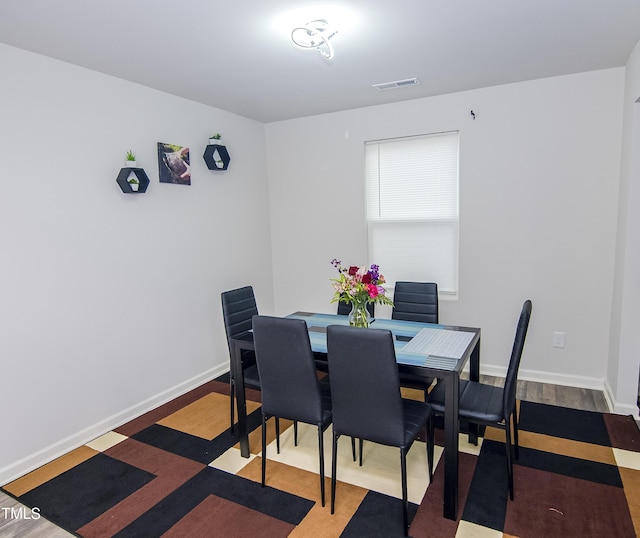 dining room featuring visible vents, baseboards, and wood finished floors