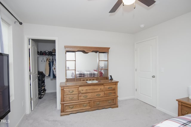 bedroom featuring a spacious closet, light colored carpet, a closet, and baseboards