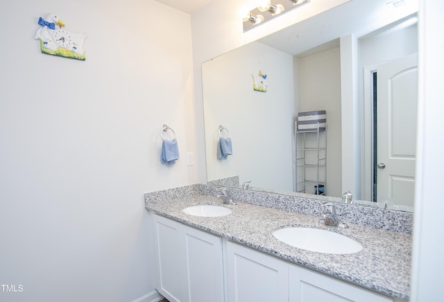 full bathroom with double vanity, baseboards, and a sink