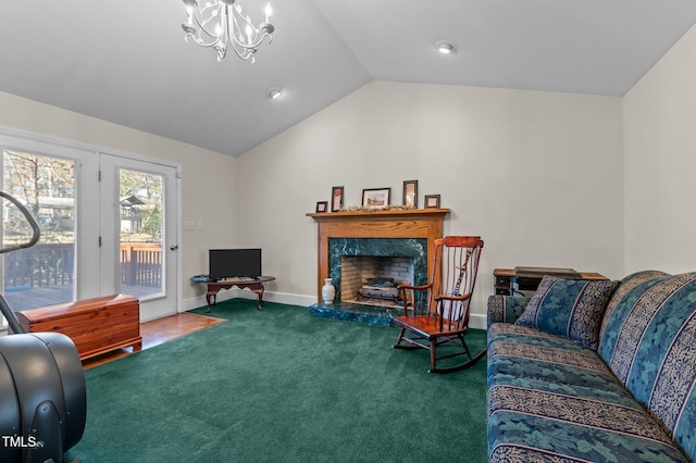 living area with baseboards, a premium fireplace, vaulted ceiling, carpet flooring, and an inviting chandelier