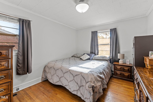 bedroom with baseboards, wood-type flooring, and crown molding