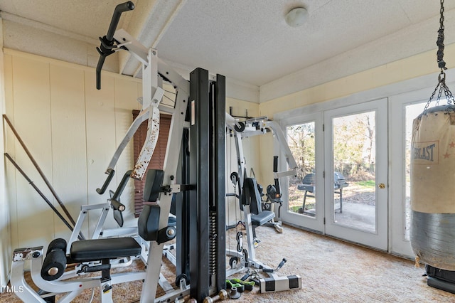 exercise area featuring a textured ceiling and carpet flooring